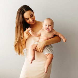 Photograph: smiling woman holding laughing baby against neutral background