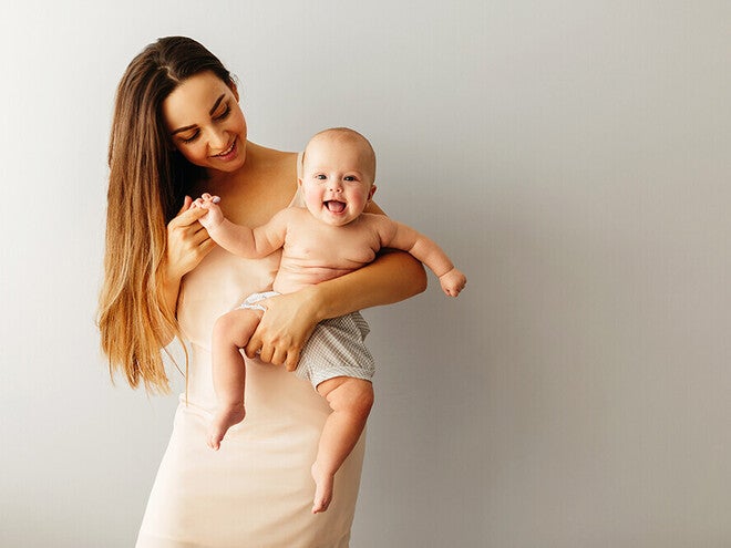 Photograph: smiling woman holding laughing baby against neutral background