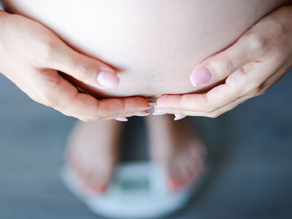 бременна жена държи ръцете на стомаха