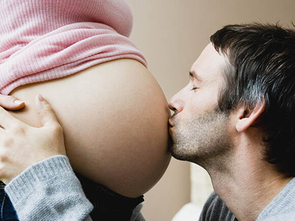мъж целува бремена жена в корема