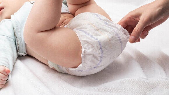 Photograph of baby having diaper fastened on white changing pad